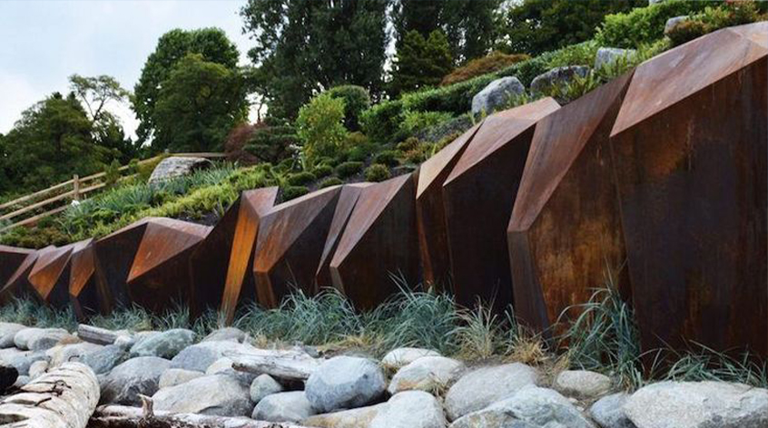 Acier Corten utilisé comme mur de soutènement géométrique dans un aménagement paysager