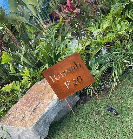 Insignes et signalétique en acier Corten avec texte découpé dans un jardin paysager