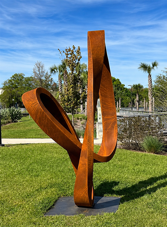 Sculpture en acier Corten monumentale et abstraite installée dans un espace paysager